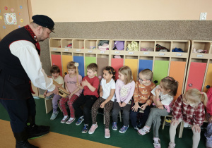 Dzieci grają na dużym bębenku trzymanym przez pana