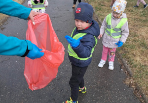 Chłopiec wrzuca do worka śmieci