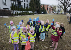 Dzieci unoszą ręce w niebieskich rękawiczkach do góry