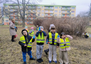 Czworo dzieci stoi na trawie na dużym placu
