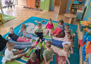 Dzieci siedzące na dywanie z nogami skierowanymi do środka koła
