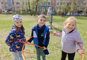 Dwie dziewczynki i jeden chłopiec trzymają duże obręcze