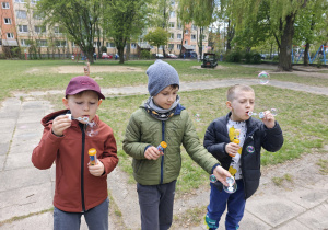 Trzech chłopców puszcza bańki mydlane