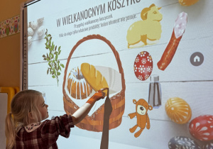 Dziewczynka dopasowuje produkty do koszyczka wielkanocnego