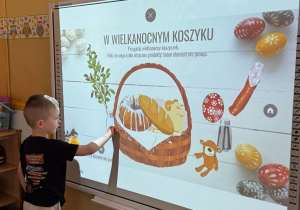 Chłopiec dopasowuje produkty do koszyczka wielkanocnego