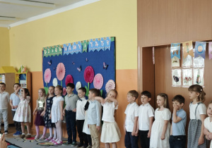 Dzieci odświętnie ubrane stoją w rządku