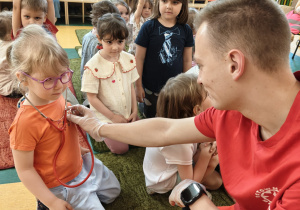 Dziewczynka słucha bicia swojego serca przez stetoskop.