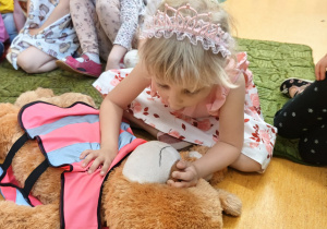 Dziewczynka pokazuje sztuczne oddychanie na misiu.