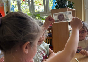 Dziewczynka ogląda banknoty pod światło