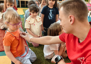 Ratownik osłuchuje dziewczynkę stetoskopem