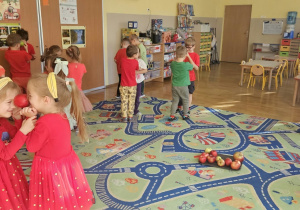 Dzieci tańczą w parach z jabłkami pomiędzy czołami