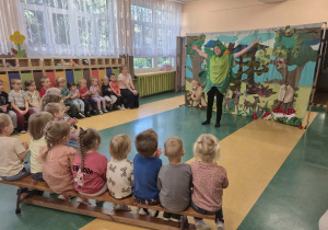 Dzieci siedzą na ławkach i patrzą na aktora