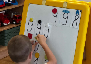 Chłopiec układa numery alarmowe na tablicy