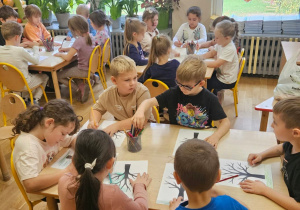 Dzieci siedzące przy stole kolorują szablony drzew