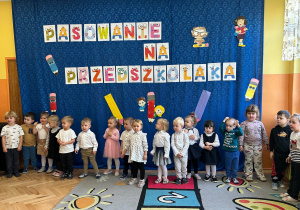 Dzieci odświętnie ubrane stoją w jednym rzędzie