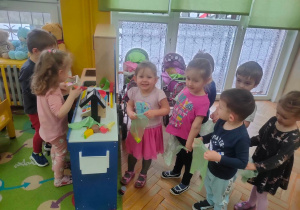 Dzieci stoją w kolejce do zabawkowego sklepiku