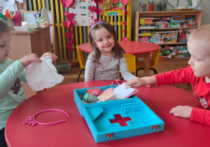 Chłopiec i dwie dziewczynki bawią się zabawkowymi akcesoriami lekarskimi