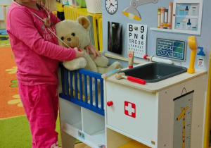 Dziewczynka bada misia w zabawkowym gabinecie weterynaryjnym