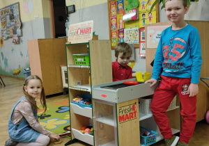 Dwóch chłopców i dziewczynka bawią się w zabawkowym sklepie