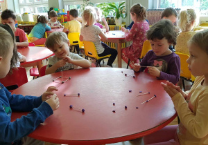 Dzieci za pomocą plasteliny łączą drewniane pateczki