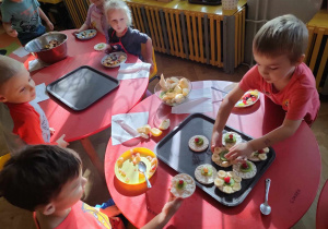 Dzieci siedzą przy stolikach i wykonują obraz z owoców Kandinsky - Abstrakcja