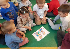 Pasowanie na Przedszkolaka - dzieci siedzą przy ułożonym obrazku