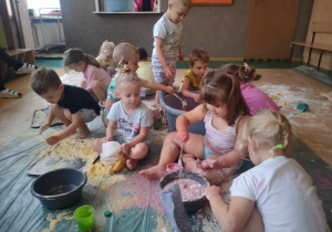 Sensoplastyka - dzieci siedzą na folii i bawią się z wykorzystaniem maki, galaretek, przelewając wodę z barwnikami spożywczymi
