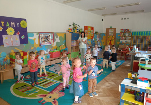 Dzieci wraz z p. Mileną bawią się w zabawę ,,Samochody", kręcąc w dłoniach kolorowymi kołkami