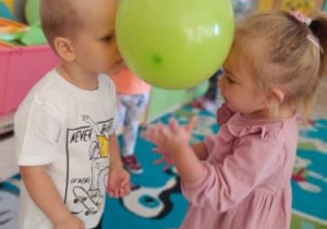 Chłopiec i dziewczynka tańczą w parze z balonem trzymanym głowami