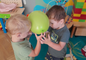 Dwóch chłopców tańczy z balonem trzymanym głowami