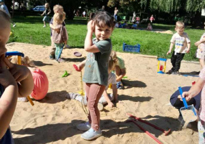 Dzieci bawią się w piaskownicy szpadelkami, grabkami i foremkami