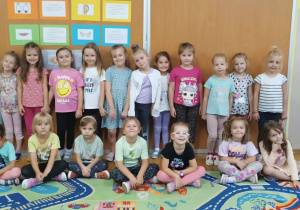Grupa dziewczynek pozuje do zdjęcia w sali przedszkolnej