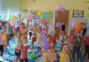 Grupa dzieci podrzuca kolorowe balony
