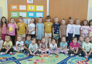 Grupa dzieci pozuje do zdjęcia w sali przedszkolnej
