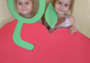 Dwie dziewczynki pozują do zdjęcia w budce fotograficznej w kształcie jabłka