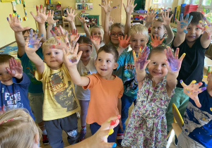 Dzieci z rękami w górze pobrudzonymi farbą