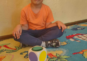 Chłopiec siedzący przed kolorową kostką do gry
