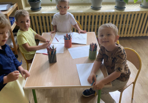 troje dzieci koloruje siedząc przy stoliku