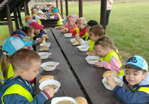 grupa przedszkolaków jedząca obiad przy drewnianym stole