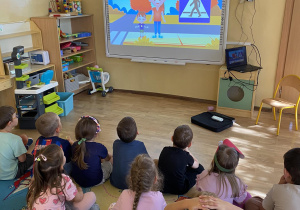 dzieci oglądające film edukacyjny na tablicy multimedialnej