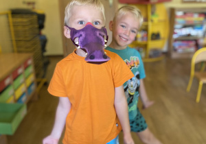 chłopiec z kolorowym ubraniu z maską krokodyla na twarzy