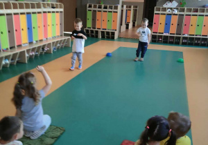Dzień Przedszkolaka - dzieci siedzą na sali gimnastycznej w dwóch drużynach i po kolei przenoszą jajko na łyżce
