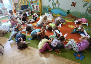 Dzień Królika - dzieci kładą się na dywanie trzymając w rękach maski królika