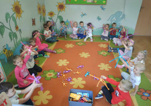 Dzieci siedzące na dywanie z kolorowymi zwierzątkami w rękach