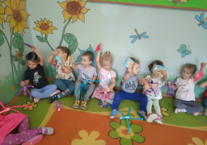 Dzieci siedzące na dywanie z kolorowymi zabawkami w rękach