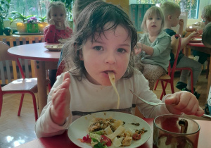 Dziewczynka je makaron z warzywami