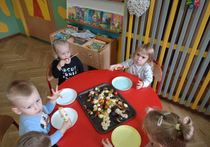 Dzieci siedzą przy stoliku i konsumują swoje koreczki