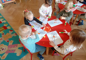 Dzieci przy stoliku wyklejają ilustracje warzy bibułą