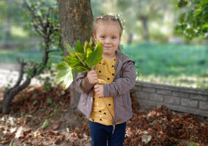 Dziewczynka pozuje z bukietem jesiennych liści