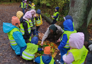 Grupa dzieci tworzy liściastą mandalę